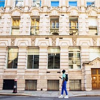 A young man wearing blue pants and a green tshirt is walking the Dr Jekyll and Mr Hyde tour in London