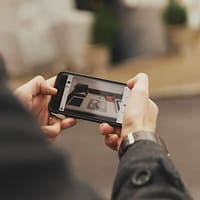 A man is holding a smartphone. On the screen a puzzle is visible