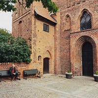 A man is sitting on a bench next to Ystad klosterkyrka