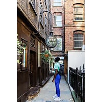 A young man in a green shirt is looking up at a sign that says Ye Olde Cheshire Cheese