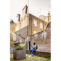 A young man is sitting on a brick wall in an alley