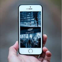A hand is holding a smartphone. On the screen is an animated image of the characters in the story.