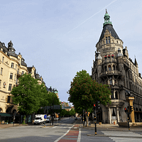 A photograph of Stureplan in Stockholm. The neo gothic buildings stretch upwards toward a blue sky.