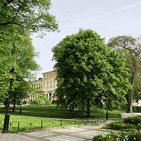 A photo of Humlegården park in Stockholm,. A graveled pathway runs between lush trees.
