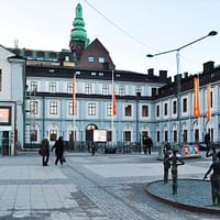 A view of Stockholm city museum at dusk. The building is a three-storey stone building in gray and blue.