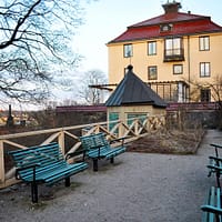 Anna Lindhagens täppa, with a panoramic view of Stockholm below. Some benches are grouped together in front of a railing.