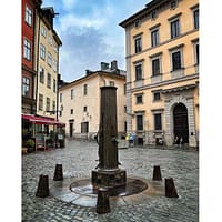 A photo of the old pump at Järntorget in Stockholm Old town. It has beein raining and the ground is wet.