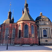 A photo of the Riddarholmen church in Stockholm. It is an imposing red brick building with several large towers.