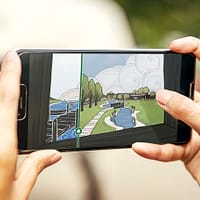 A close-up of two hands holding a smartphone. on the screen is an illustration of a shoreline.