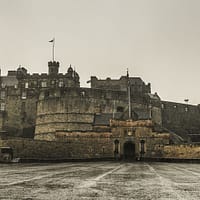 A photo of the Edinburgh Casle on a dreary day. Rain is glistening in the castle courtyard.