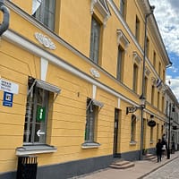 A photo of a street in Helsinki, with yellow mortared buildings lining a cobblestone street.