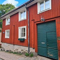 A photo of a two-storey red wooden house with a green door.