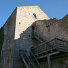 A photograph of the Kajsarn prison tower against a very blue sky. There is a wooden staircase leading up the side of the tower.