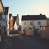 A photo of Strandgatan in Visby. There is a cobblestone street with low white, pink and yellow stone buildings lining it.