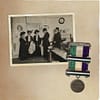 An old album with a photo of a group of women and a medal in the suffragette colors
