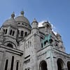 A photo of a part of th sacre ceur church in Paris. The white stone contrasting against a clear blue sky.