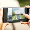 A close-up of two hands holding a smartphone. on the screen is an illustration of a shoreline.