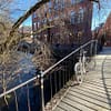 A photo of a small wooden bridge across the Akerselva river in Oslo. A bike is leaning against the bridge railing.