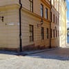 A photo of a street on Riddarholmen in Stockholm. Yellow, mortared buildings are lining a narrow cobblestone street. At the end of the street you can see clear blue sky and water.