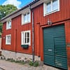 A photo of a two-storey red wooden house with a green door.