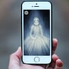 A close up of a hand holding a smartphone. On the screen is an illustration of a ghost queen.