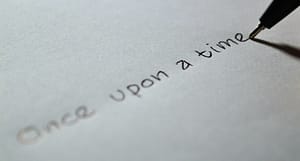 A pen writes "once upon a time" across a white sheet of paper
