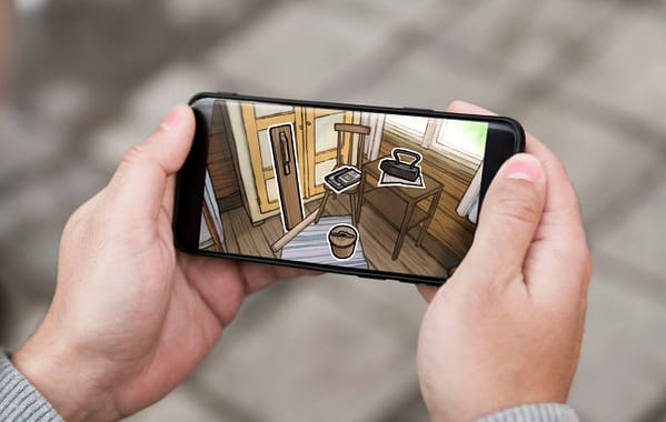 Two hands are holding a smart phone. On the screen is an illustration of the interior of a small cabin in the early 1900's.