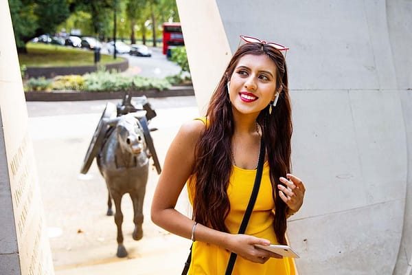 A young woman in a yellow dress is exploring the animals in war memorial in London
