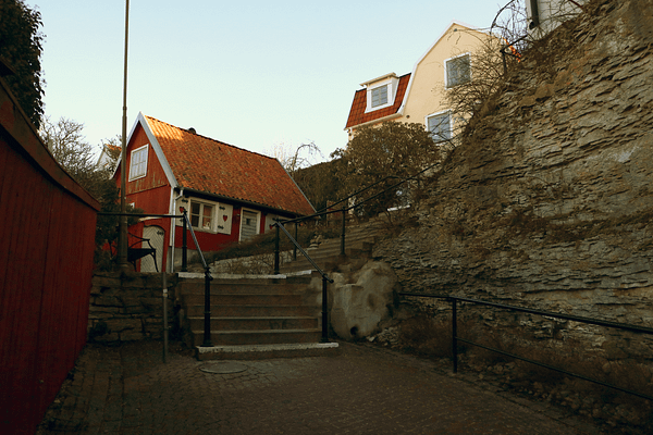 A small red wooden house with a stone staircase leading up beside it.