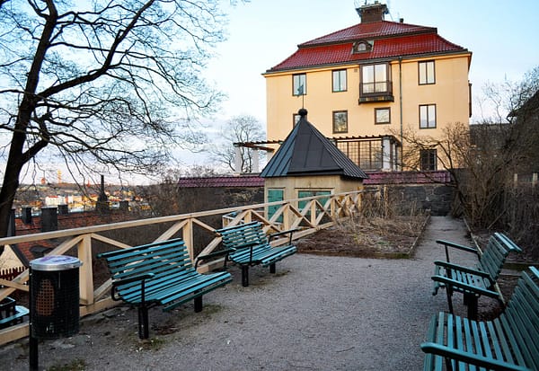 Anna Lindhagens täppa, with a panoramic view of Stockholm below. Some benches are grouped together in front of a railing.
