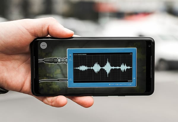 A hoto of a hand holding a smartphone. There is an illustration of a radio wave visible on its screen.