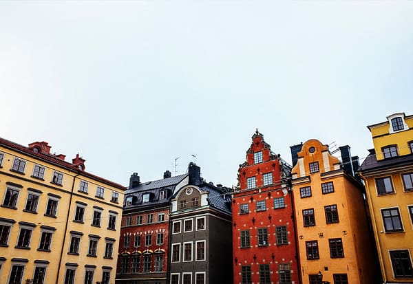 A photograph of a Stockholm Old town skyline, with colorful mortared buildings.