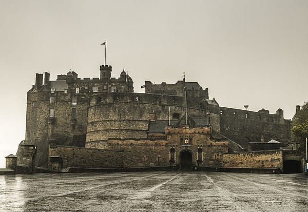 A photo of the Edinburgh Casle on a dreary day. Rain is glistening in the castle courtyard.