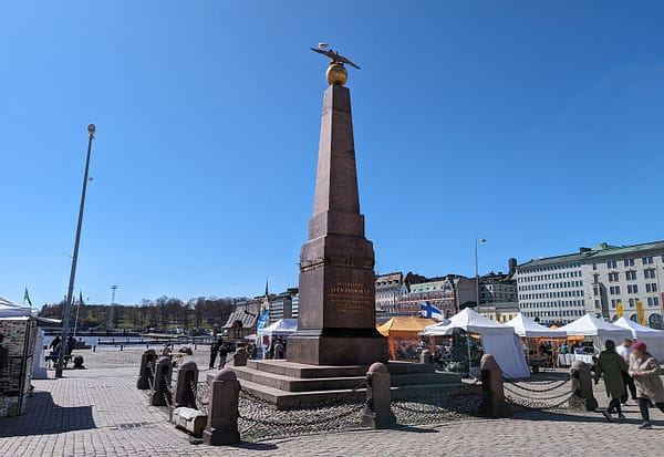 A photo of the obelisk statue at Kauppatori square in Helsinki on a day with clear blue sky.