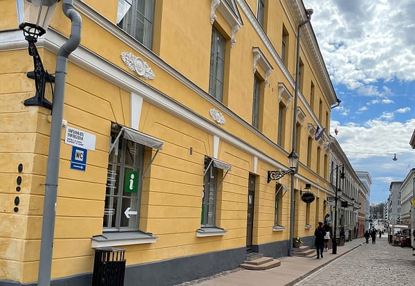 A photo of a street in Helsinki, with yellow mortared buildings lining a cobblestone street.