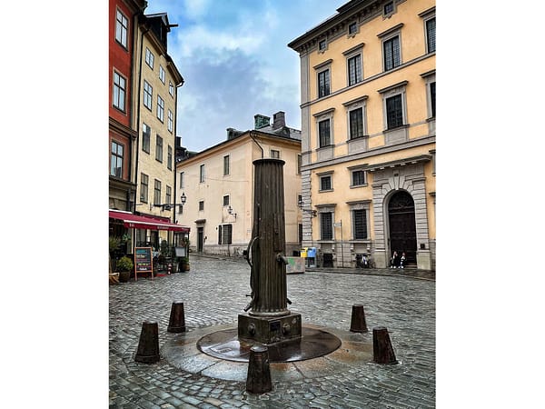 A photo of the old pump at Järntorget in Stockholm Old town. It has beein raining and the ground is wet.