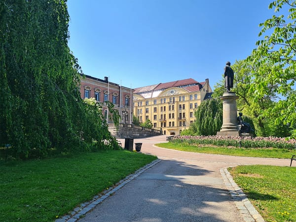 A photo of the University park in Uppsala on a sunny day. yo ucan see the Carolina library in the background.