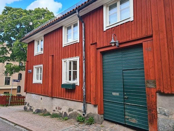 A photo of a two-storey red wooden house with a green door.