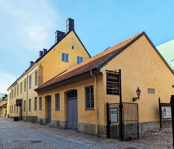 A photograph of the Kronhusbodarna market area in Gothenburg. It consists of a series of low, yellow stone buildings around a cobble stone square.